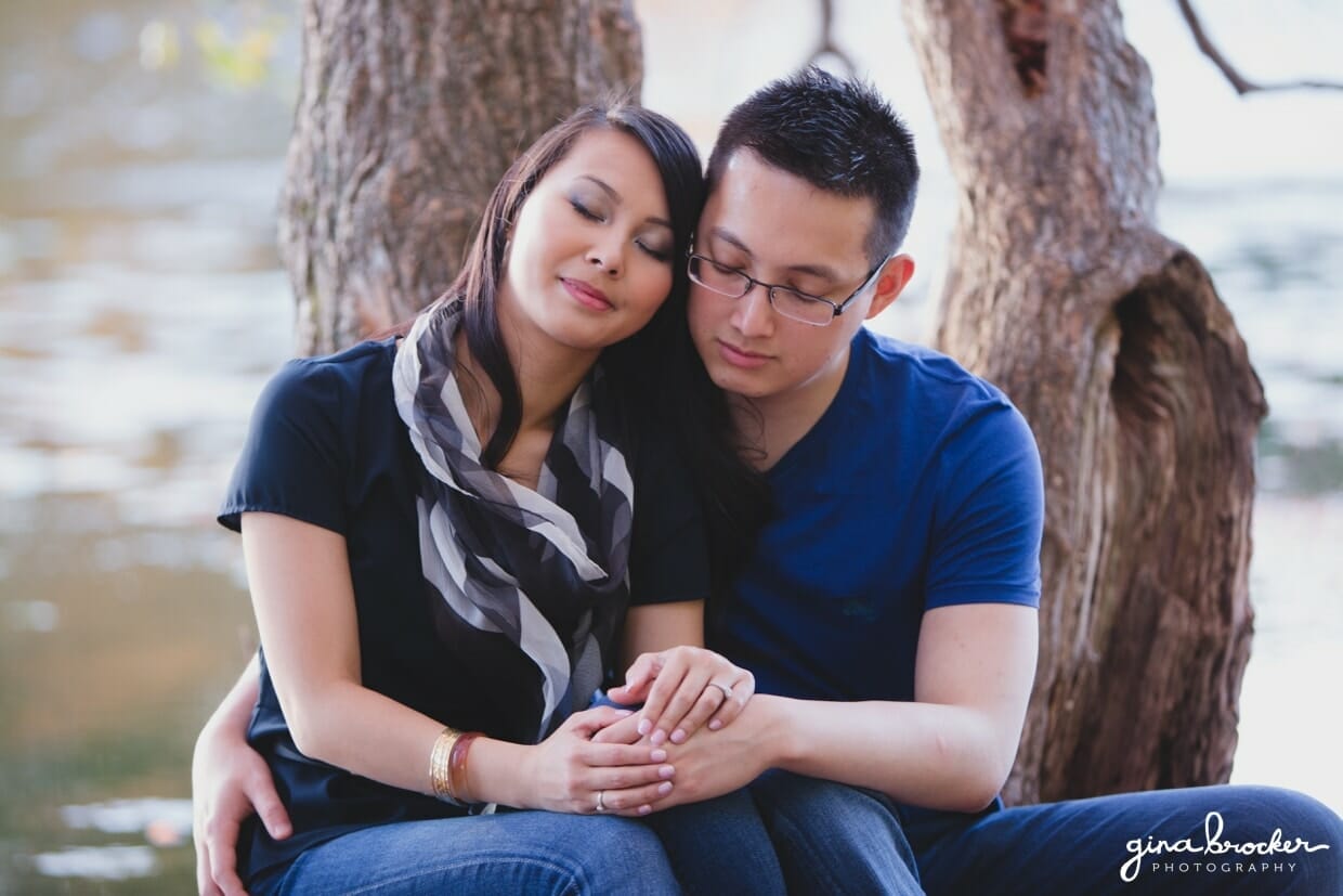 A couple cuddle and relax along the charles river during their fall engagement session in boston