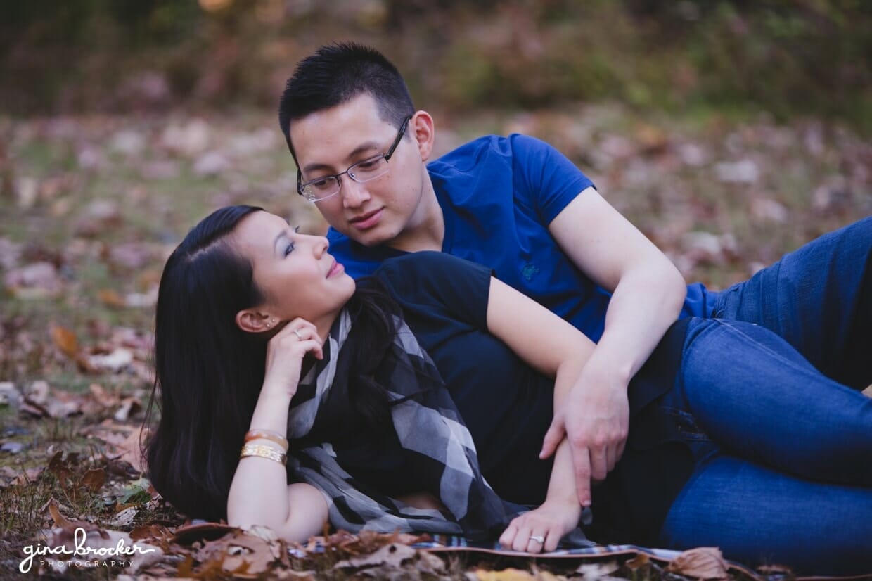 A couple lay together in the grass during their fall engagement session in boston