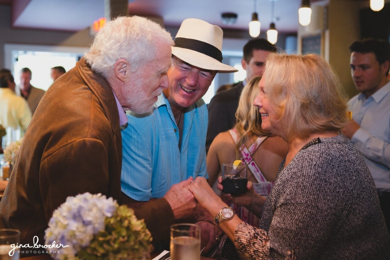 A sweet photograph of guests talking and laughing during a wedding rehearsal dinner at Back Yard BBQ restaurant in Nantucket, Massachusetts
