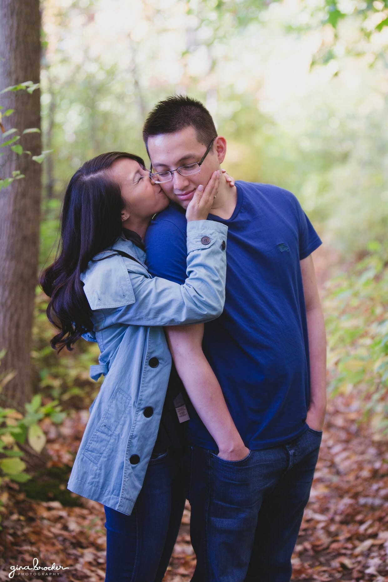 A couple share a sweet kiss together in the woods during their fall engagement session
