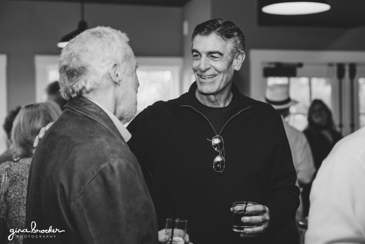 Photojournalistic photograph of two men talking during a wedding rehearsal dinner at the Back Yard BBQ restaurant in Nantucket, Massachusetts