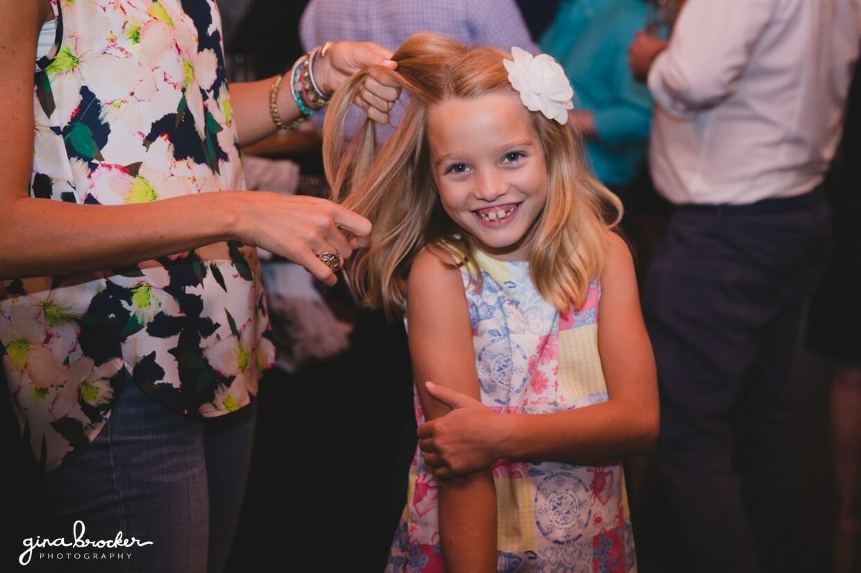A little girl gets her hair braided during a Nantucket wedding rehearsal dinner at the Back Yard BBQ restaurant in Massachusetts
