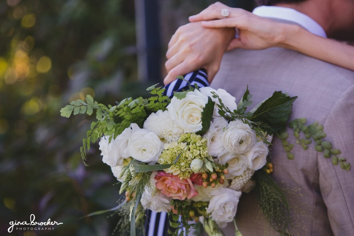 A detail of a bride holding a natural and nautical inspired bouquet of white, peach and cream roses during their Nantucket Wedding at Westmoor Club