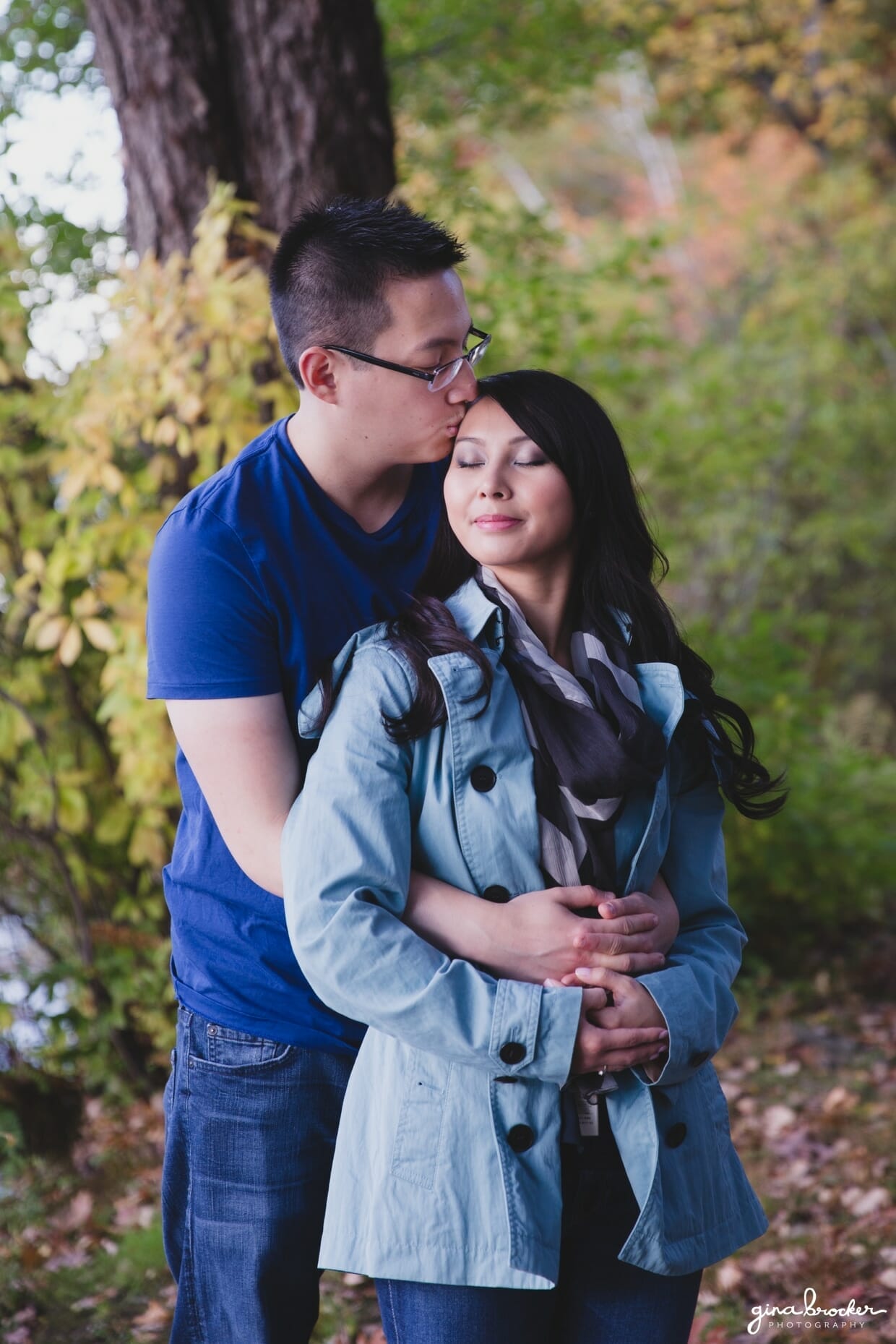 A couple cuddle in the woods during their fall engagement session in boston