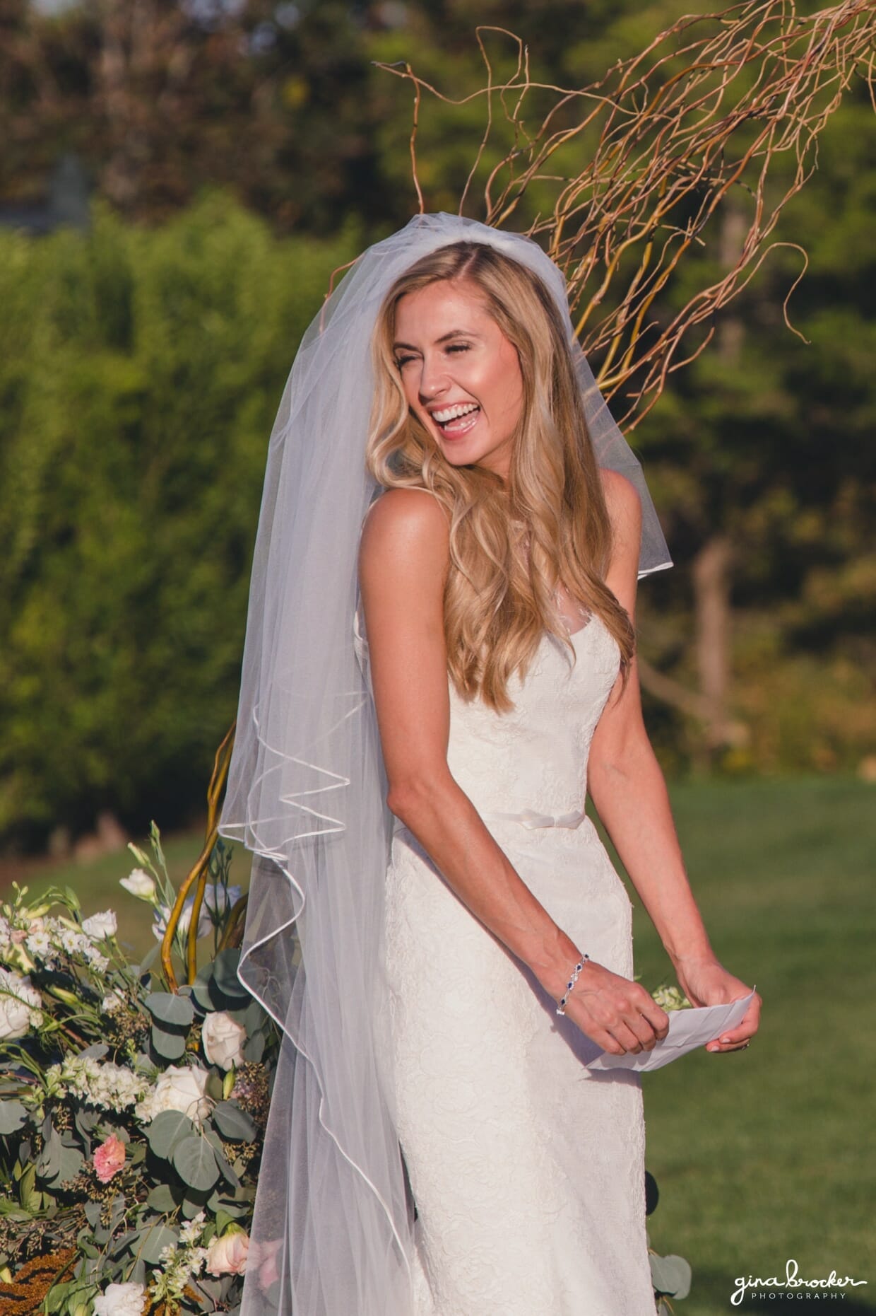 A bride looks back at her guests and smiles during her sunny outdoor wedding ceremony at the Westmoor Club in Nantucket, Massachusetts