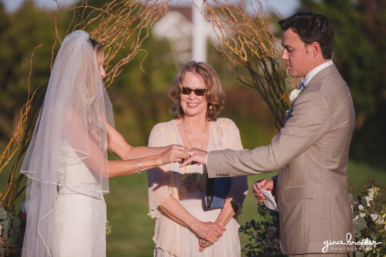 The bride and groom exchange rings during their sunny outdoor wedding ceremony at the Westmoor Club in Nantucket, Massachusetts