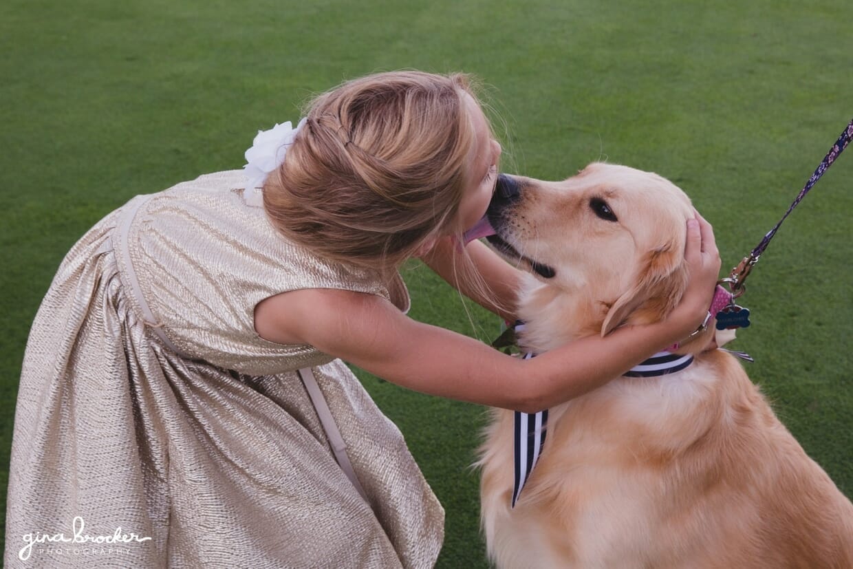 A documentary style photograph of a flower girl kissing a dog at a Nantucket Wedding