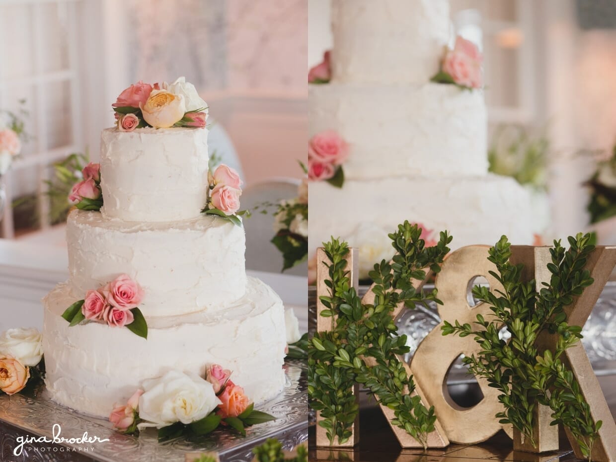 A simple three tiered cream wedding cake with fresh pink and peach flowers and a gold and ivy sign at a Westmoor Club Wedding in Nantucket, Massachusetts