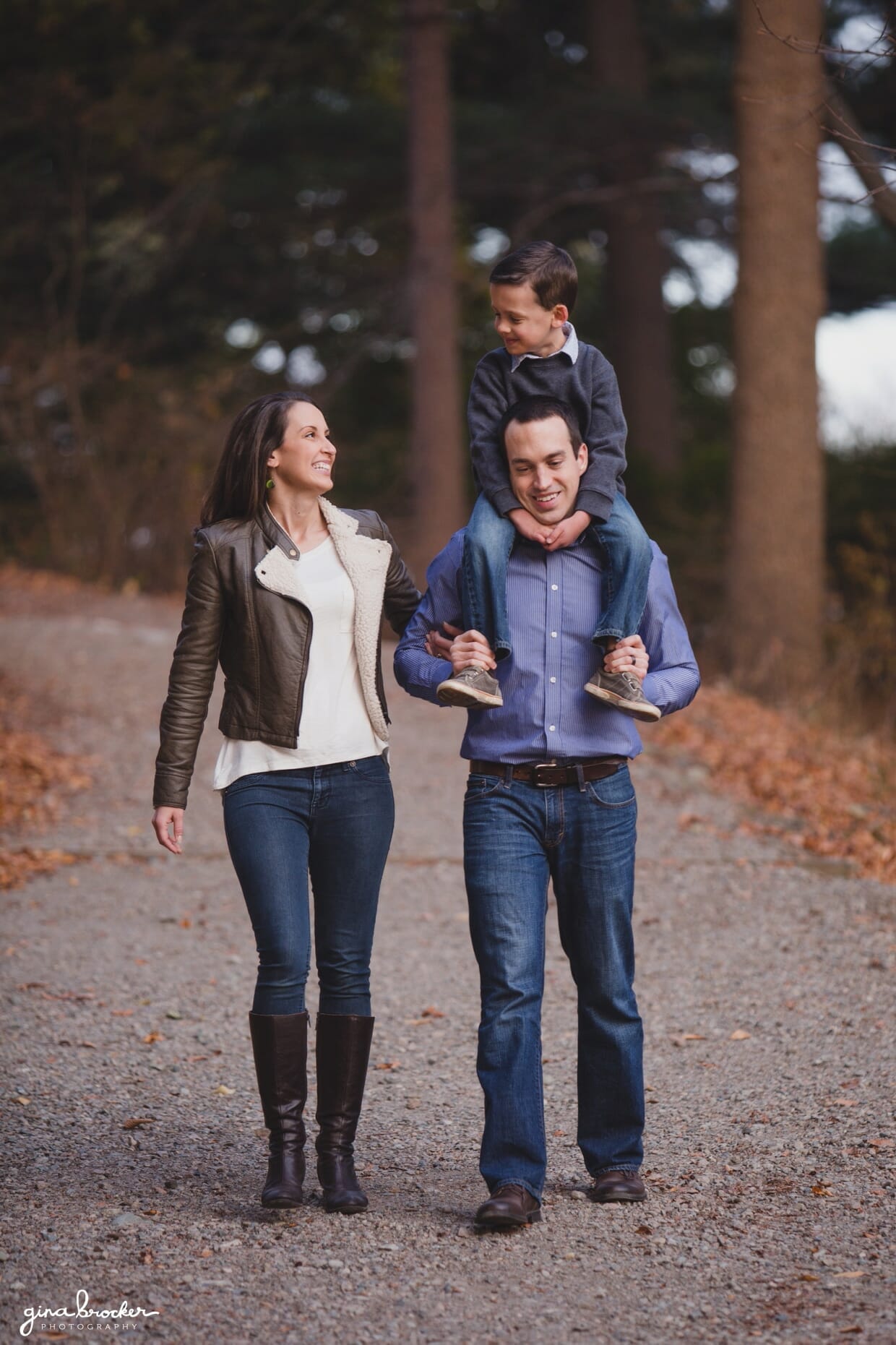 A sweet photograph of a family walking together down a tree lined path during their family photo session in Boston's Arnold Arboretum