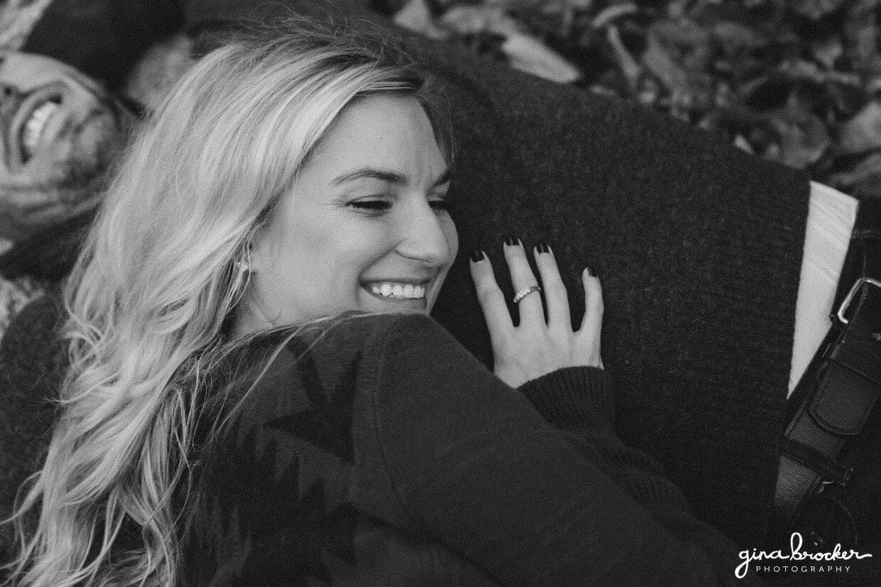 A sweet photograph of couple laying together and laughing on a blanket during their fall couple session in Boston's Arnold Arboretum