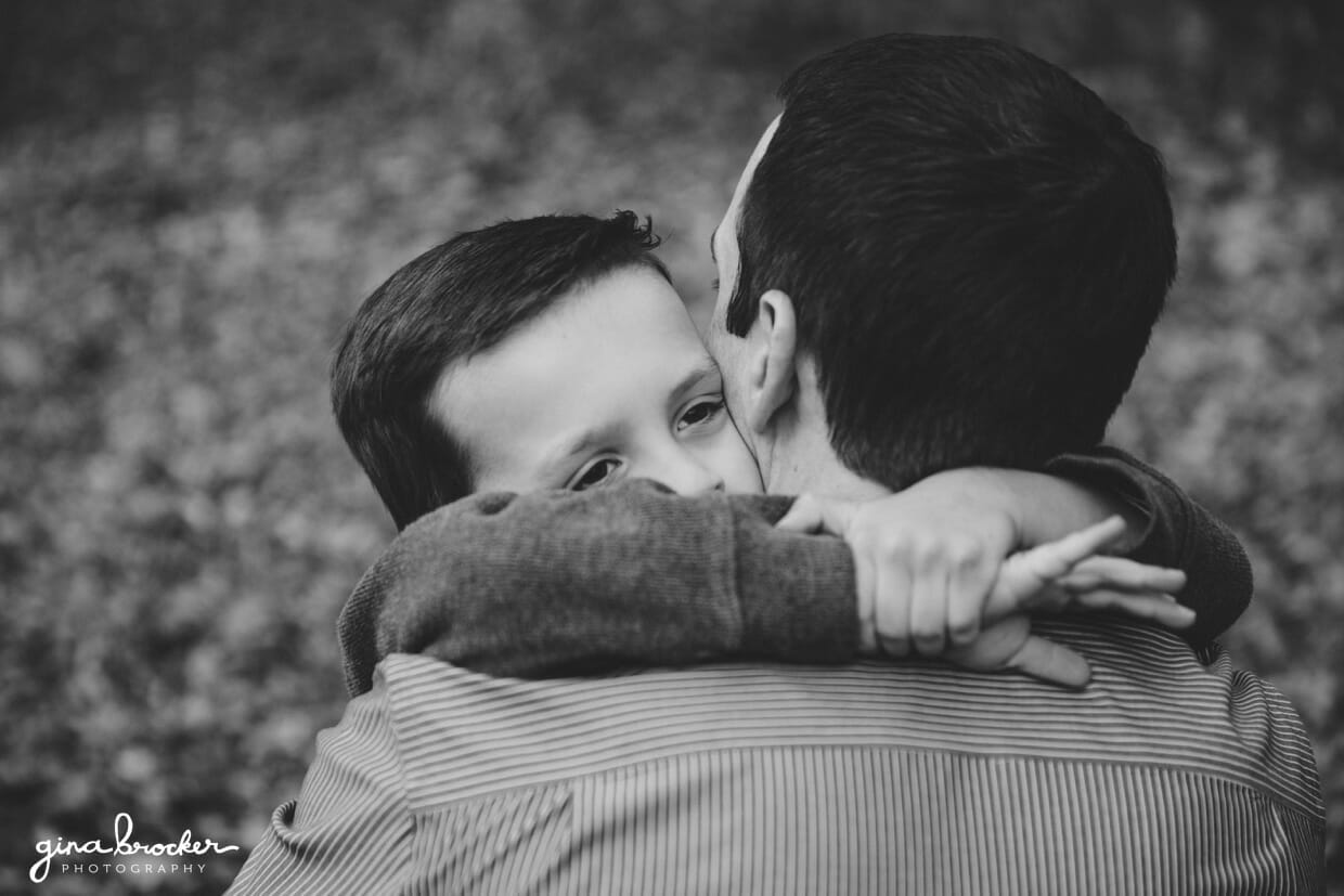 A close up photograph of a son hugging his father during their family photo session in Boston, Massachusetts