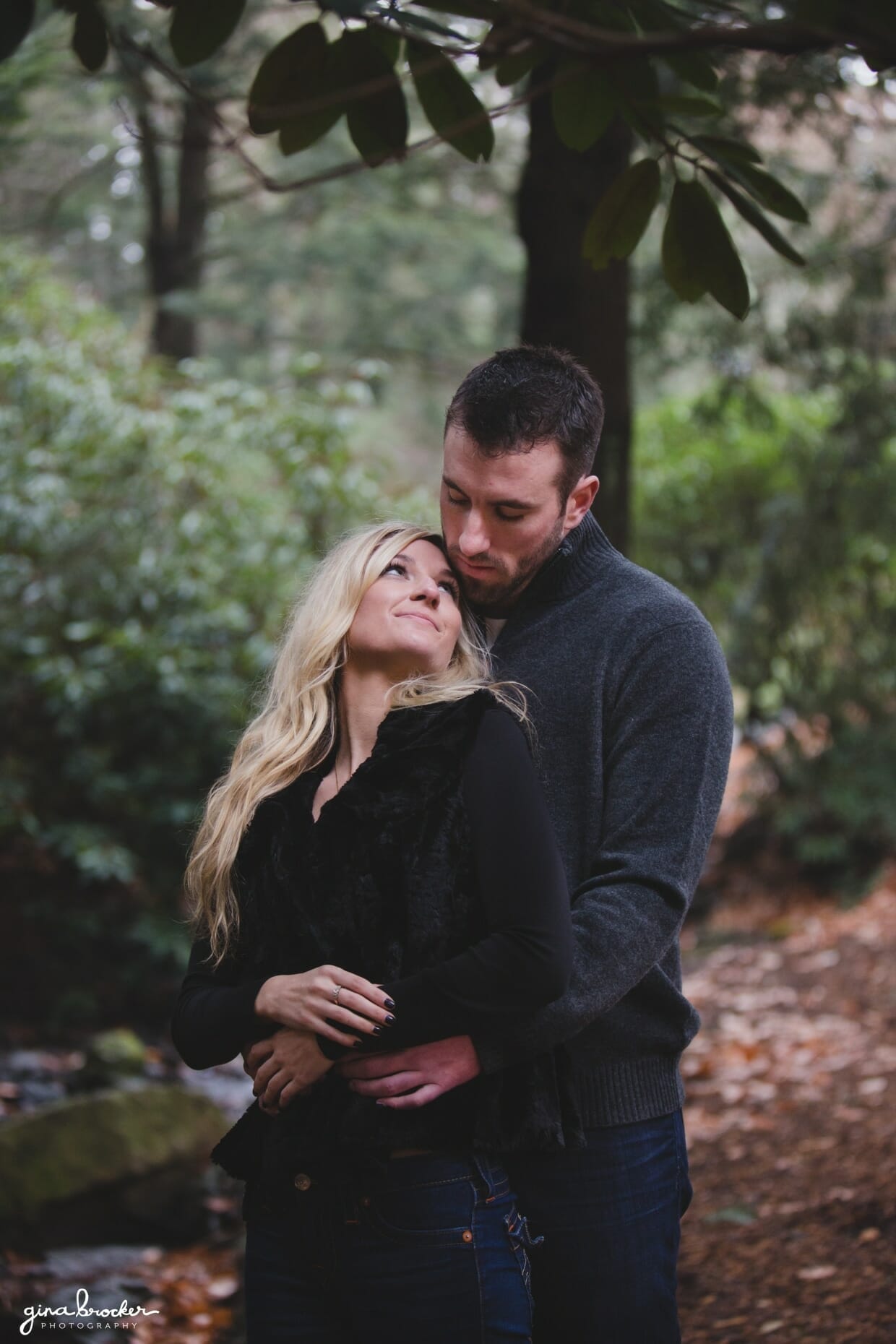 A romantic and sweet photograph of a couple cuddling in the woods during their fall couple session at the Arnold Arboretum in Boston, Massachusetts