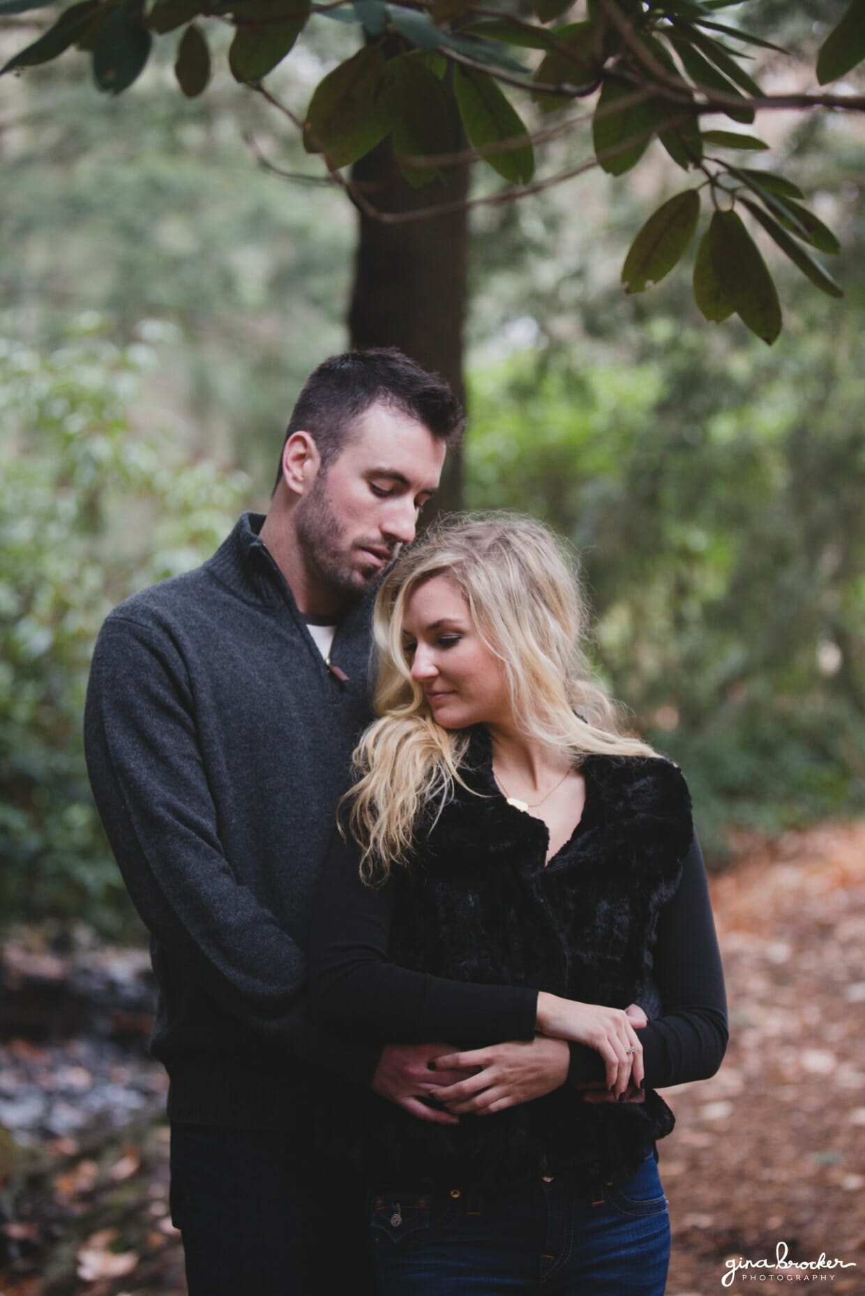 A romantic photograph of a couple cuddling in the woods during their fall couple session in Boston's Arnold Arboretum