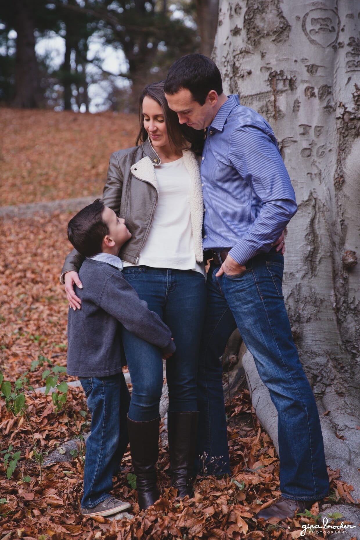 A portrait of a family beside a tree during their fall family photo session in Boston's Arnold Arboretum