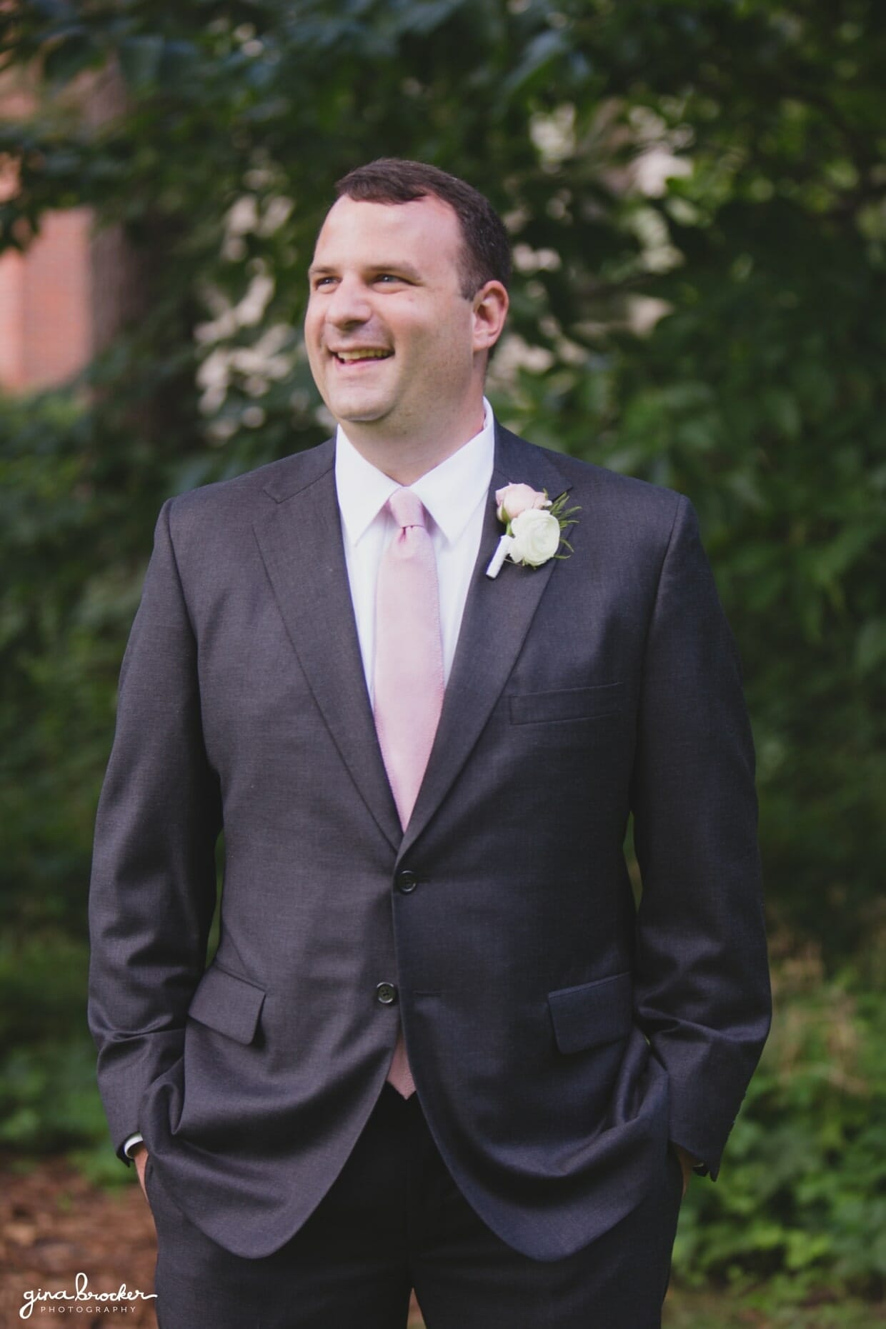 A candid portrait of a groom laughing as he waits for his bride to arrive to the first look during their classic and elegant wedding in Boston, Massachusetts