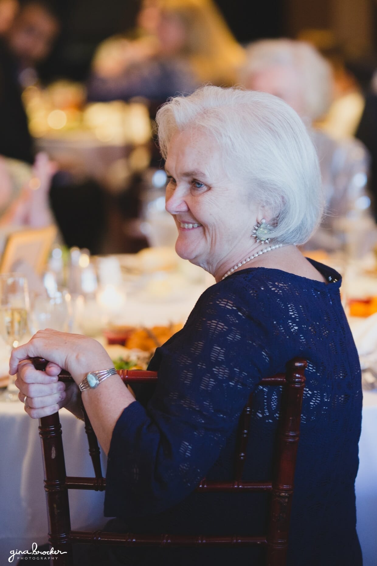 Candid photograph of the mother of the bride smiling during the speeches at a classic and elegant Boston Wedding