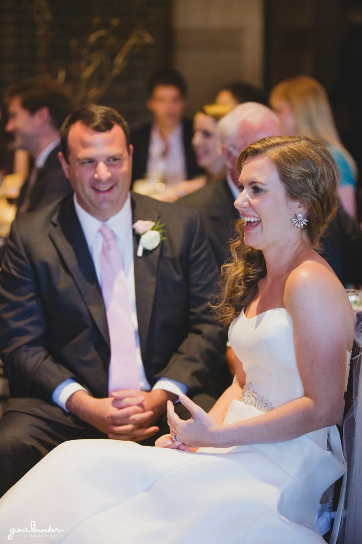 A bride and groom laugh during the speeches at their classic and elegant Boston wedding in Massachusetts