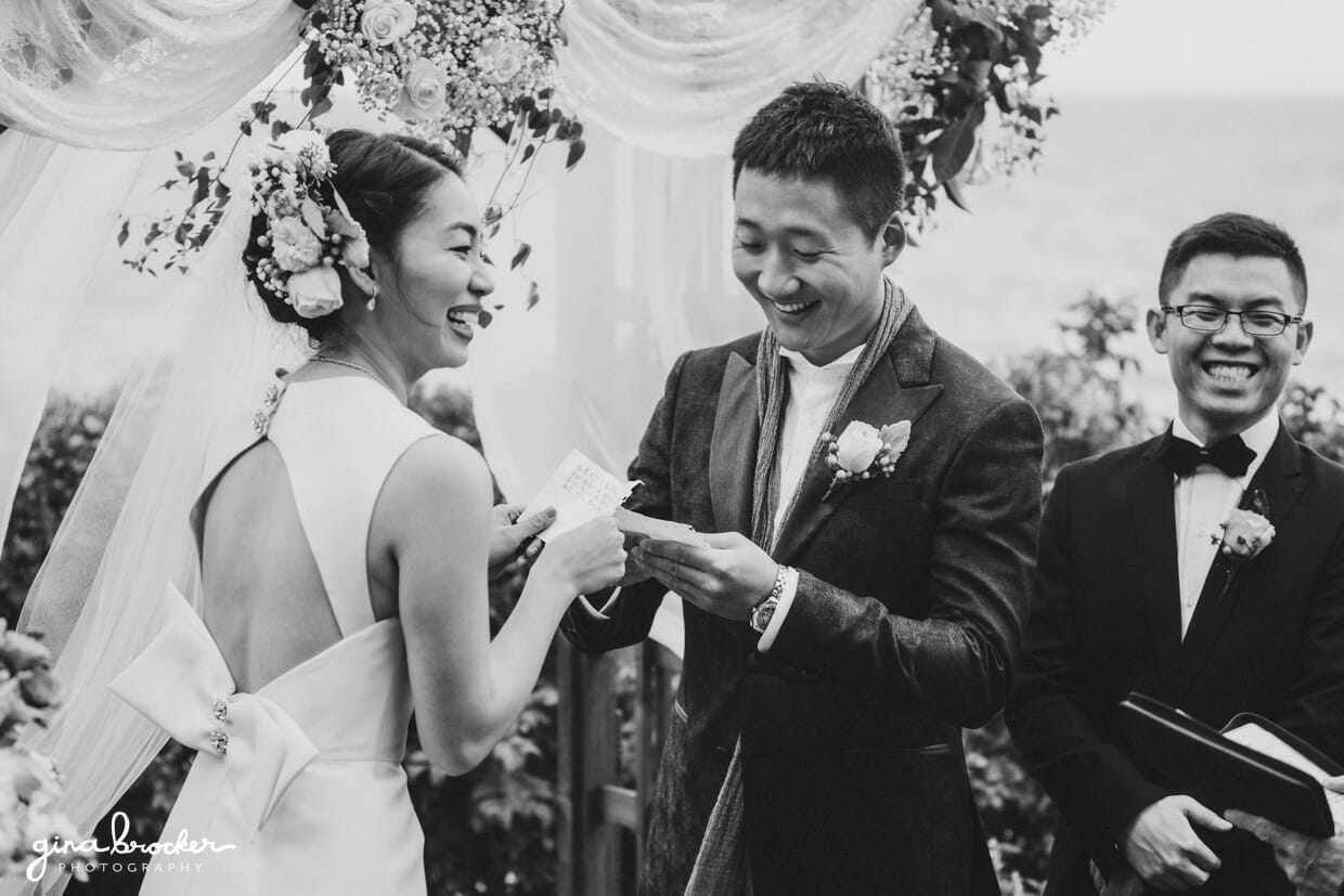 A bride and groom laugh while they read their vows during their outdoor wedding in Boston, Massachusetts