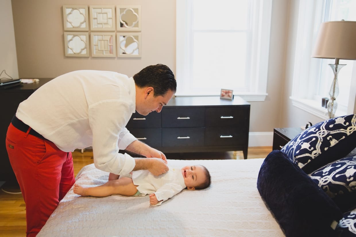 A father dresses his baby boy during a documentary in home family photo session in Boston.
