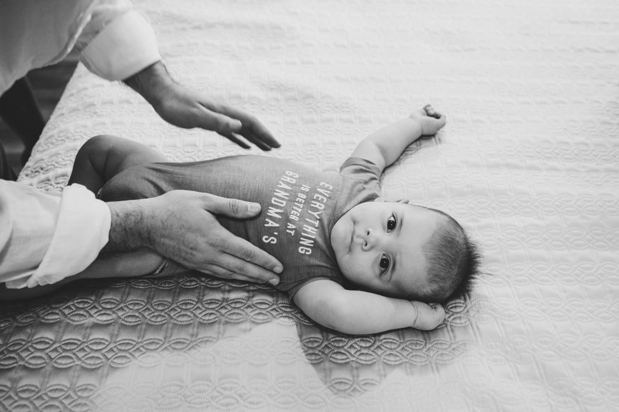 A sweet candid portrait of a baby boy getting dressed during a Boston family photo session at home.