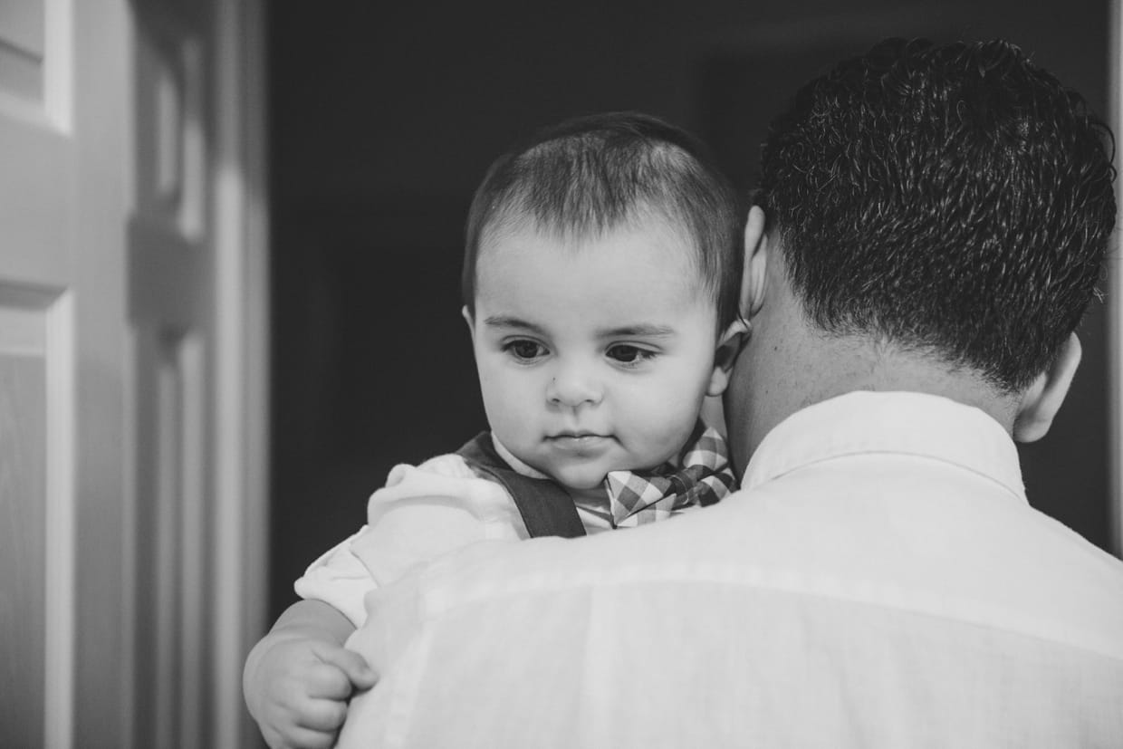 A father carries his baby boy down the hall during a Boston family photo session in the home.