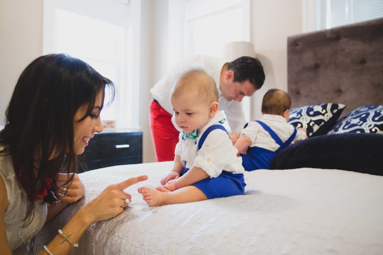 Parents dress their twin baby boys before their in home family photo session in Boston