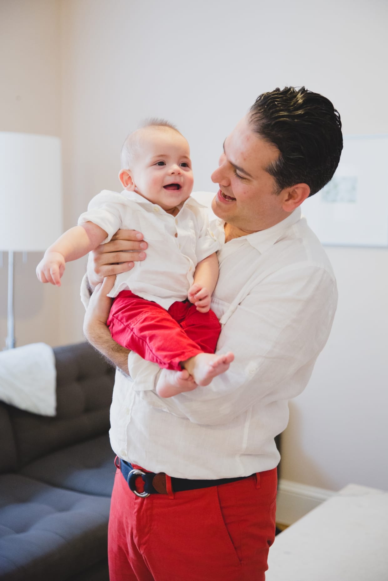 A candid and fun portrait of a father holding his baby boy in their Boston home. 