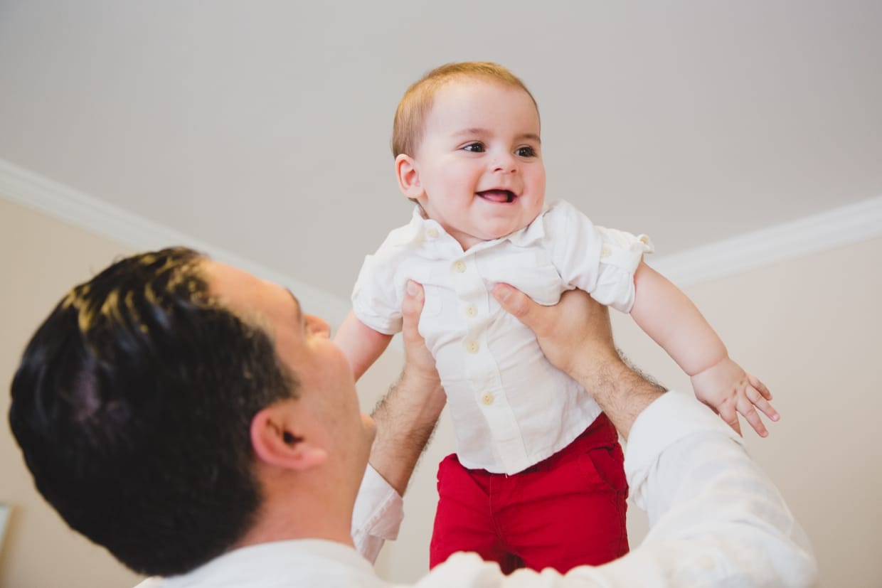 A natural and beautiful photograph of a father playing with his baby boy during their Boston family photo session at home.