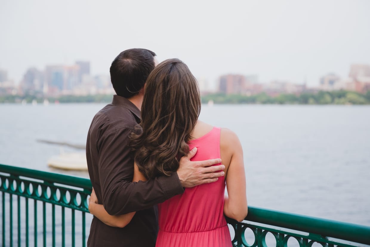 A beautiful photograph of a couple looking at the Boston skyline from the Charles River during their couple session.