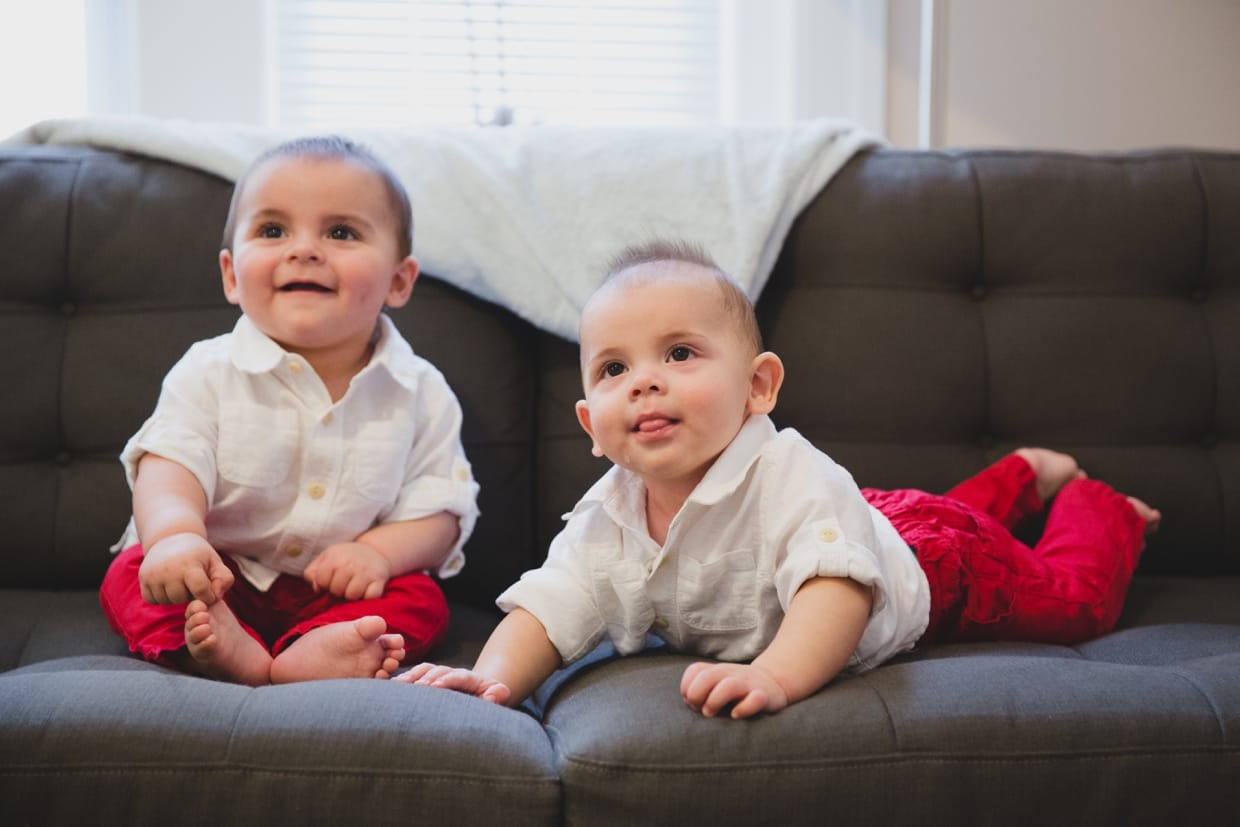 A sweet portrait of twin baby boys on the couch during a family photo session in their Boston home.