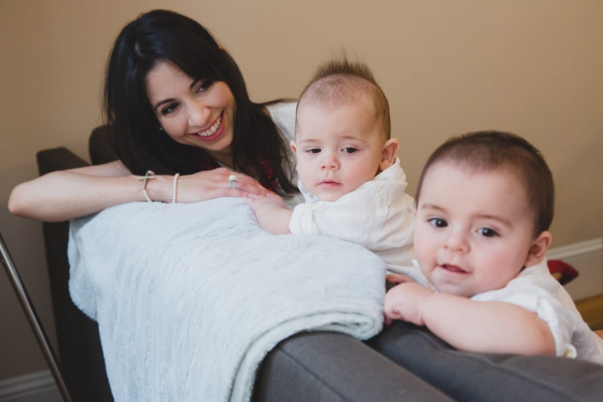 A mother plays with her sons on the couch during an in home family photo session in Boston.