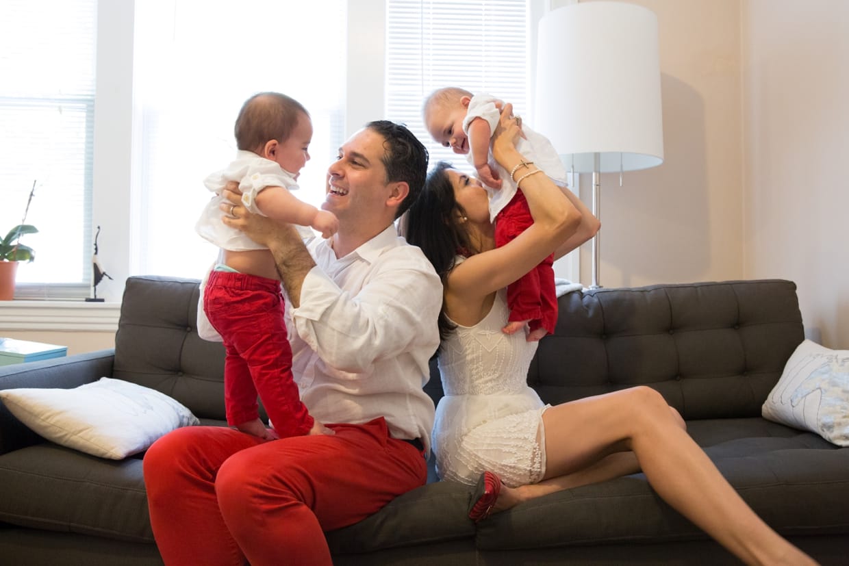 Parents play with their baby twin boys on the couch during their in home family session in Boston.