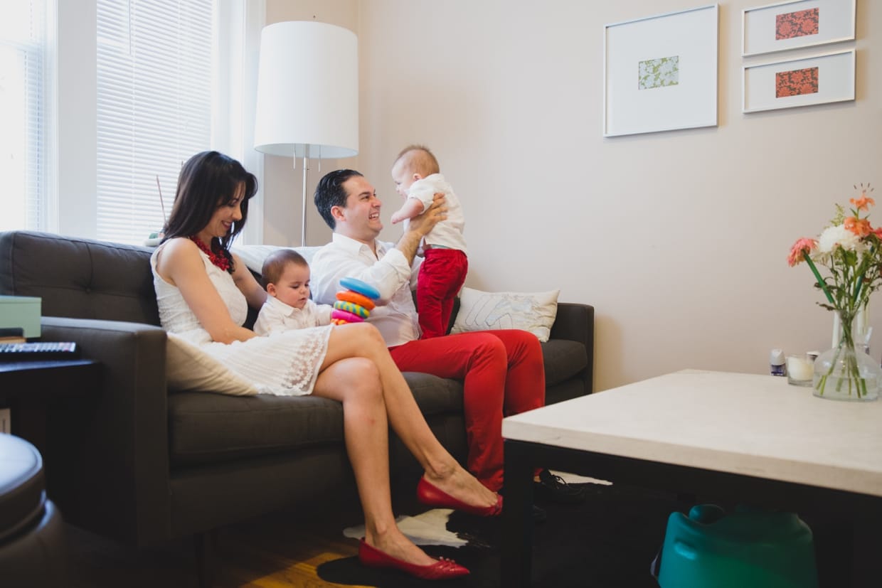 A documentary photograph of parents playing with their twin baby boys during a Boston family photo session at home.