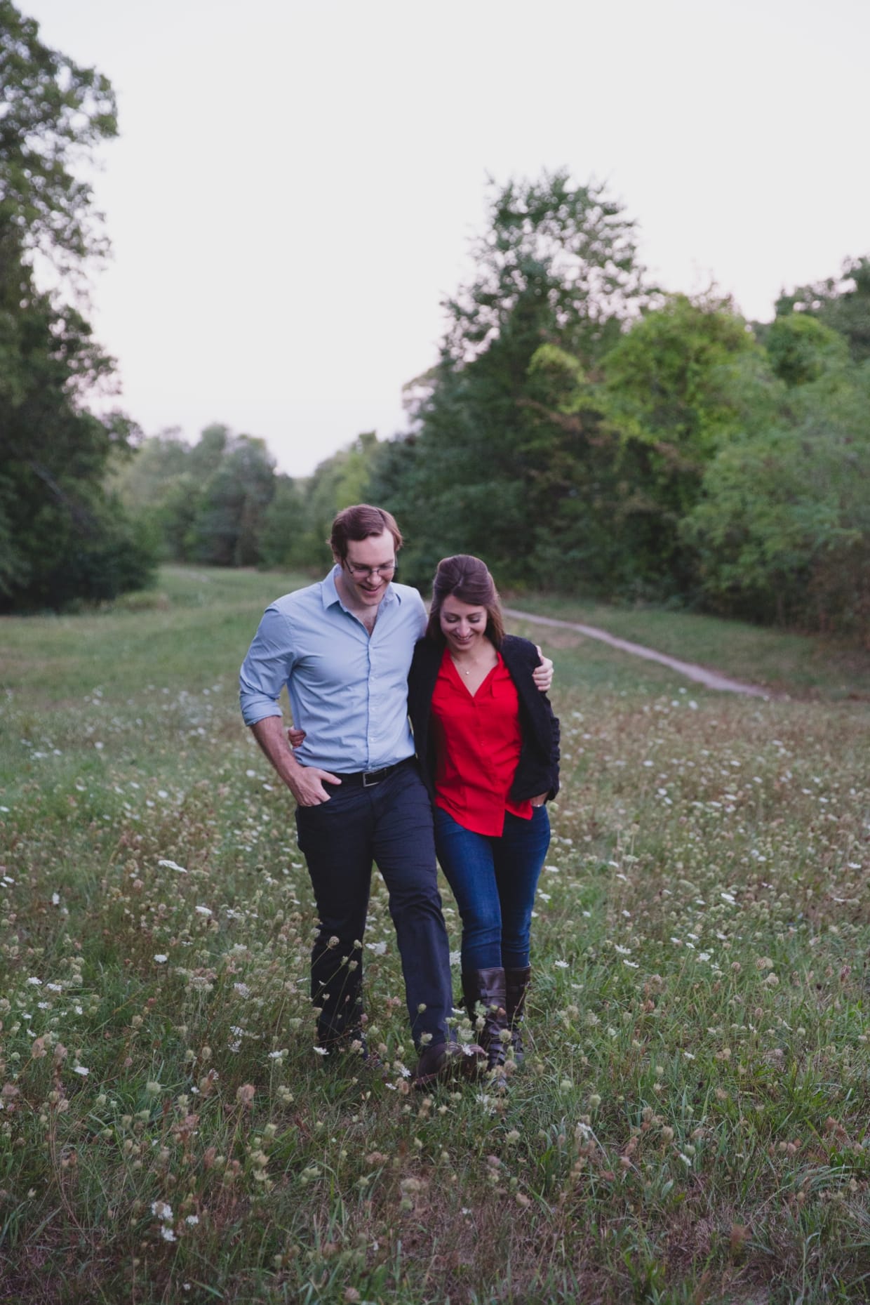 A sweet and natural photograph of a couple walking together in a field during their engagement session at Boston's Arnold Arboretum