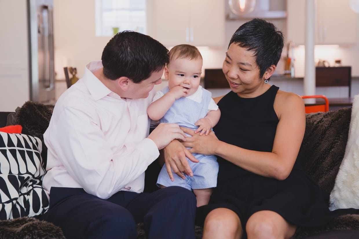A beautiful and natural photograph of a family sitting together on a couch during their in home family photo session in Jamaica Plain