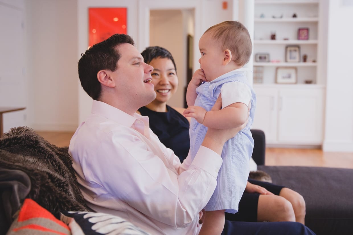 A cute photograph of a father holding his son on the couch during a Jamaica Plain family photo session at home.