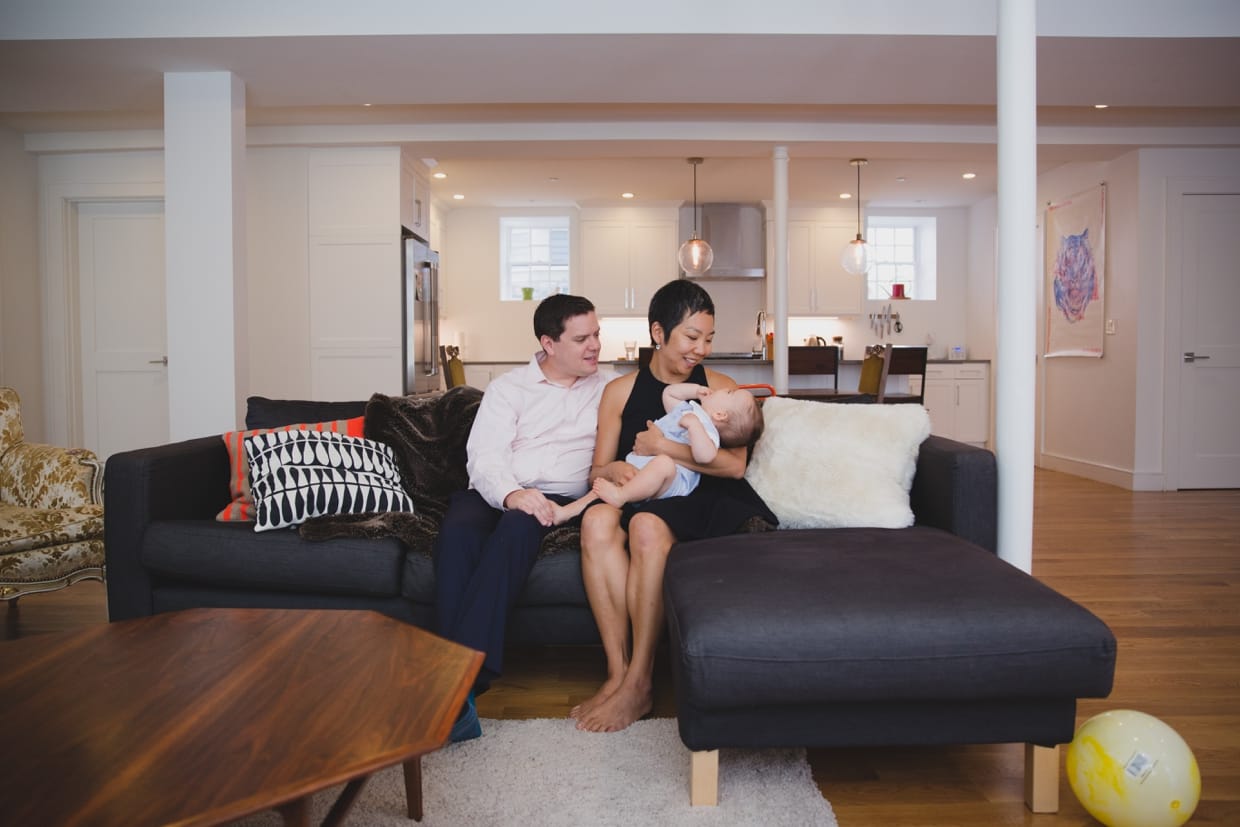 A documentary photograph of a family sitting on the couch in Jamaica Plain during their in home family photo session