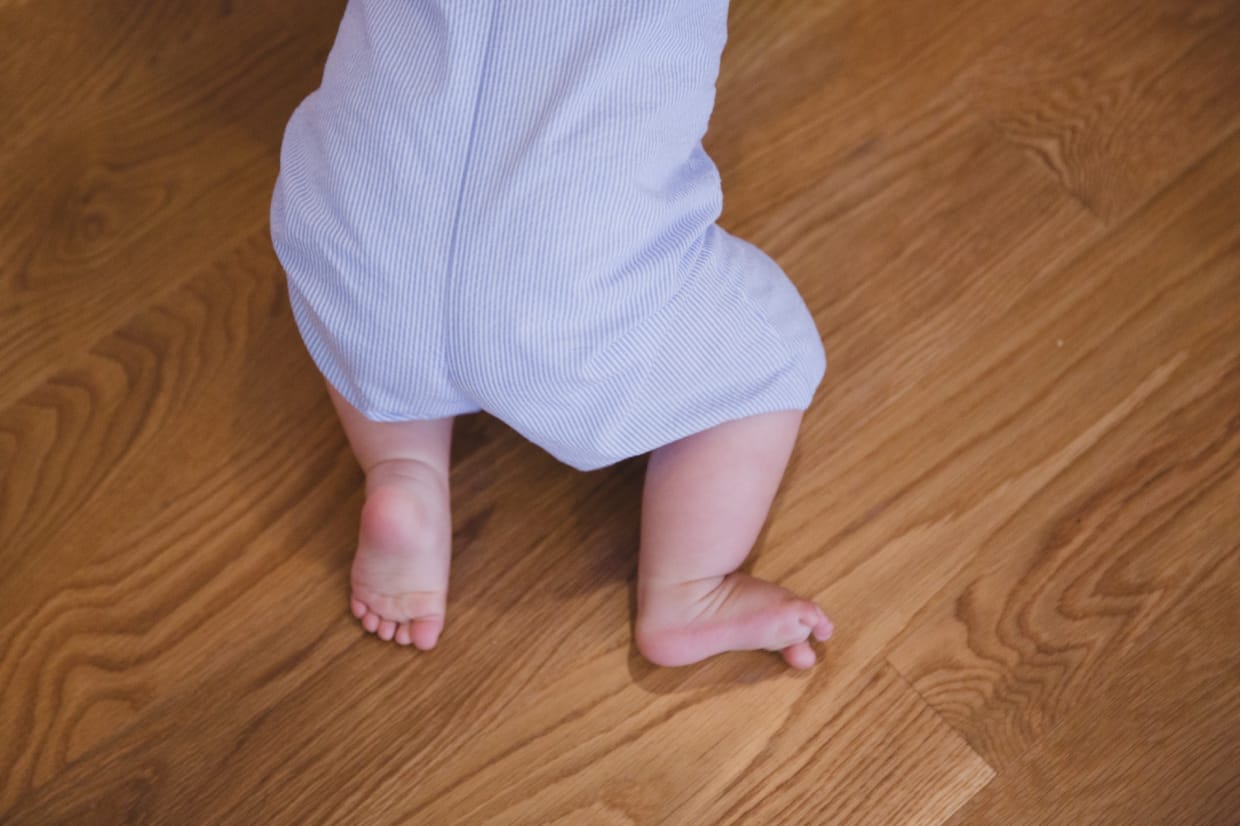 A detail of a baby boys feet while he crawls to mother during their Jamaica Plain family photo session at home