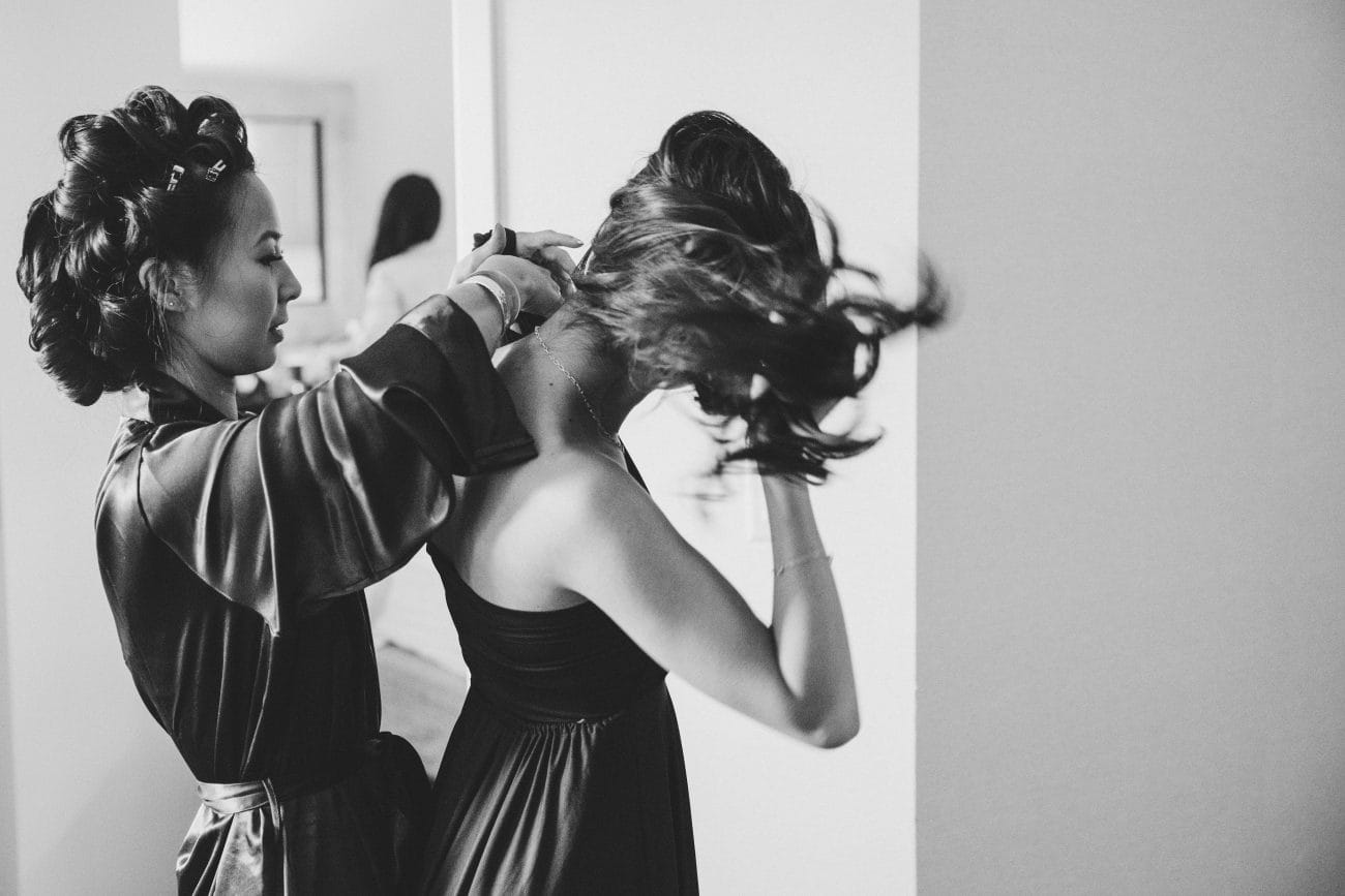 A bride helps her bridesmaid fasten her dress before her vietnamese tea ceremony in Boston