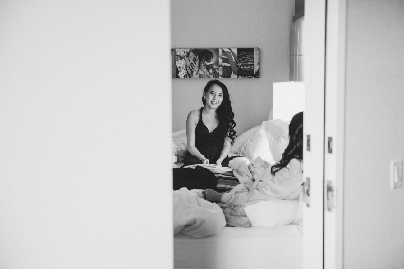 A documentary style photograph of bridesmaids talking on the bed on the morning of a Vietnamese Tea Ceremony in Boston