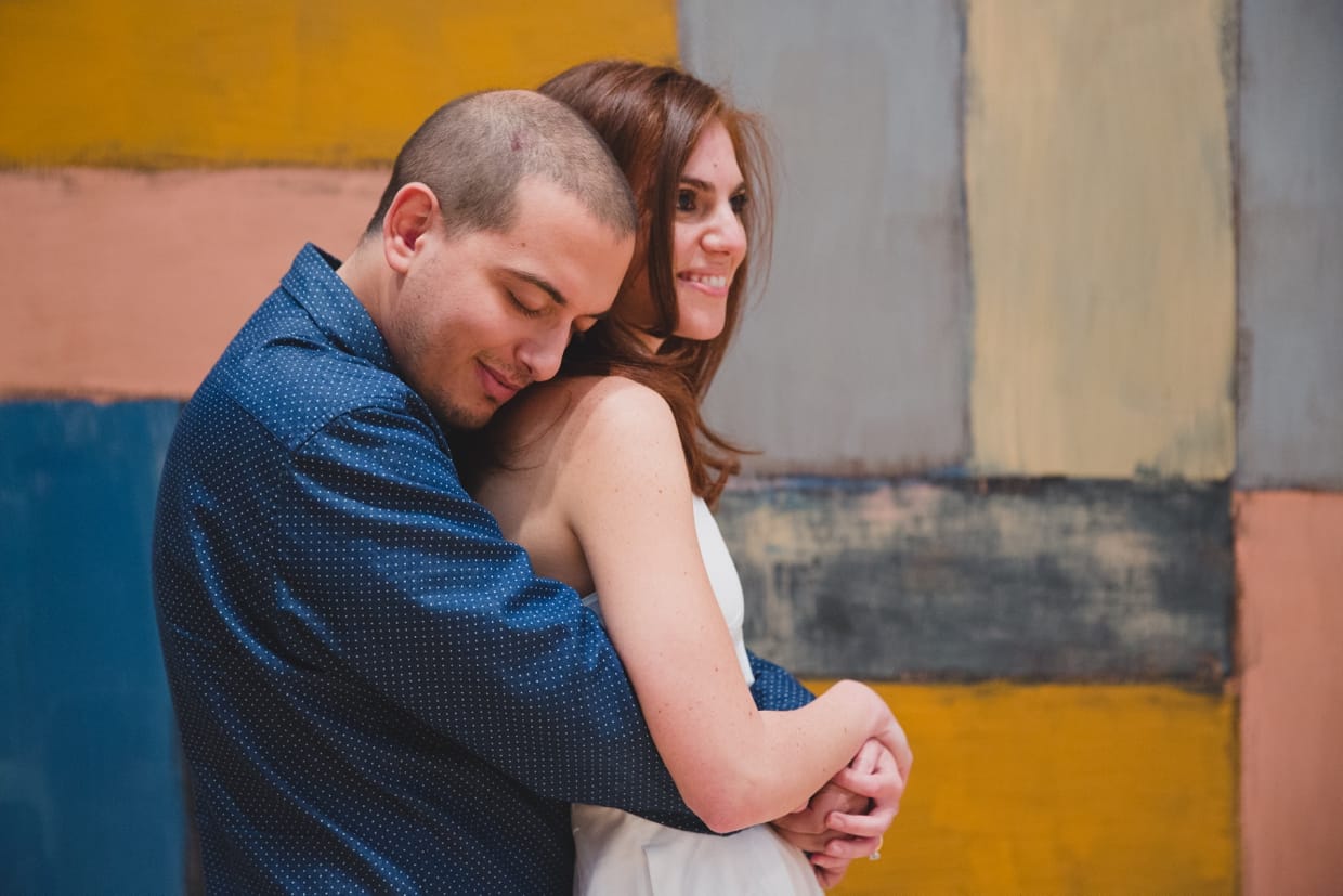 A sweet photograph of a couple hugging in front of a contemporary painting during their engagement session at the Museum of Fine Arts in Boston