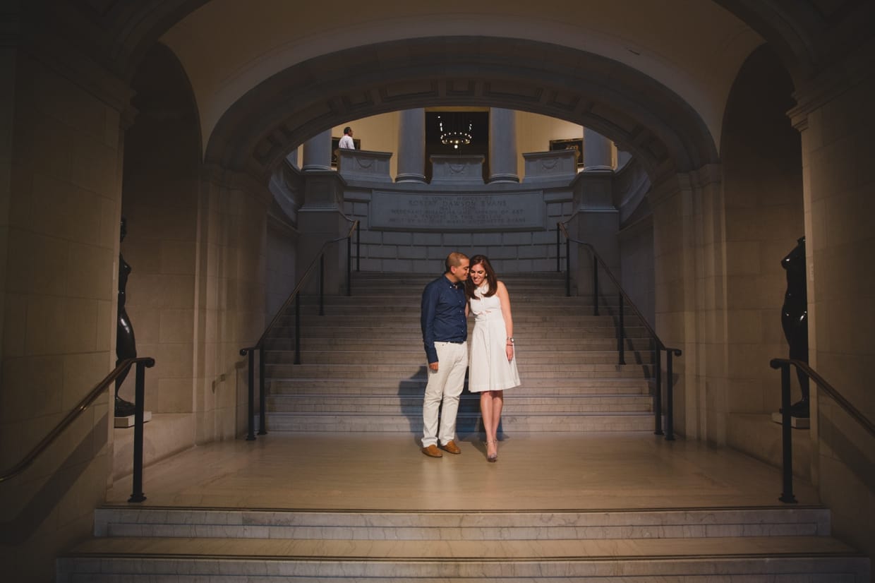A romantic and sweet photograph of a couple sharing a moment on the steps of the Museum of Fine Arts during their engagement session in Boston, Massachusetts