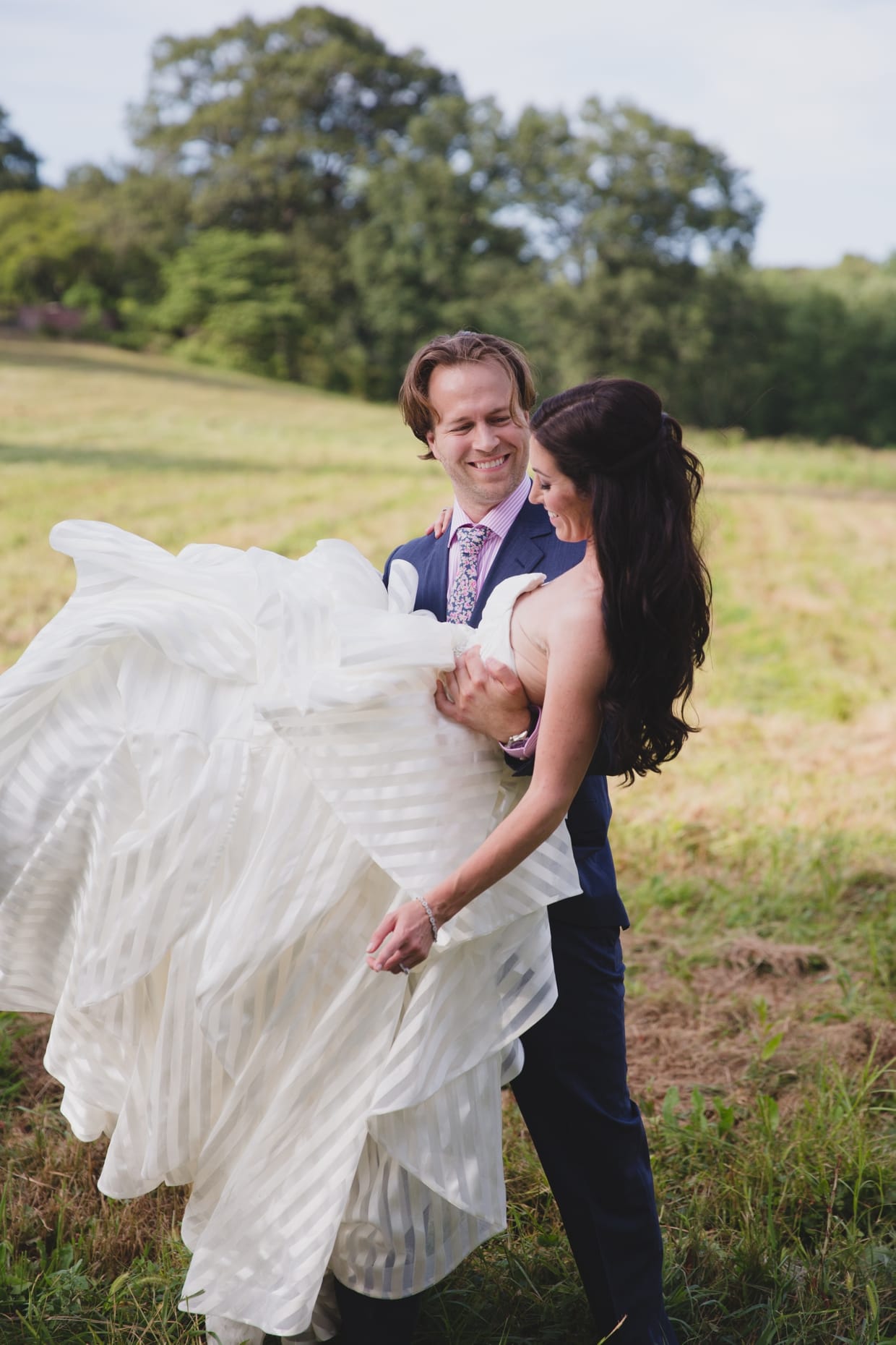 A cute portrait of a groom spinning his bride around before their backyard wedding in Massachusetts