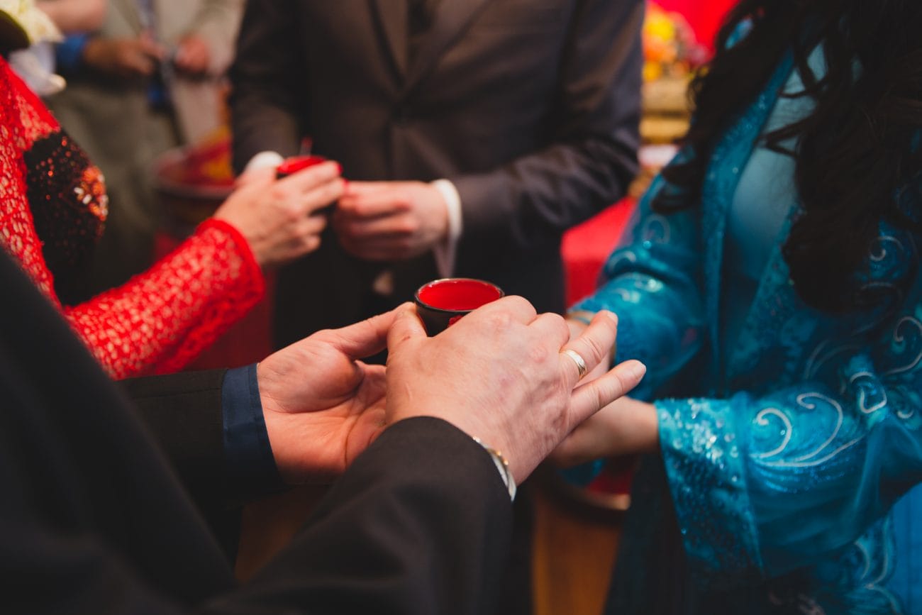 A documentary style photograph of a bride and groom passing tea to the groom's parents during a vietnamese tea ceremony in Boston