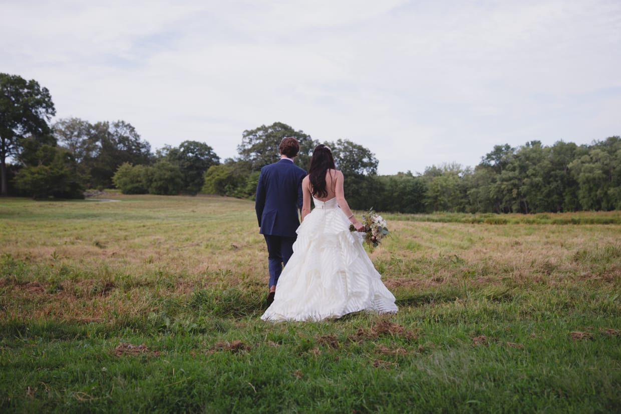 A beautiful photograph of a couple walking through the Minute Man park during their first look