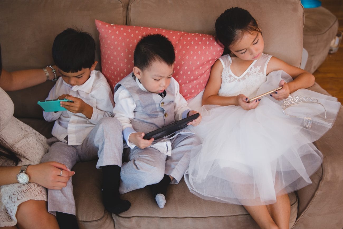 A candid photograph of the flower girl and ring bearers playing video games during the vietnamese tea ceremony in Boston