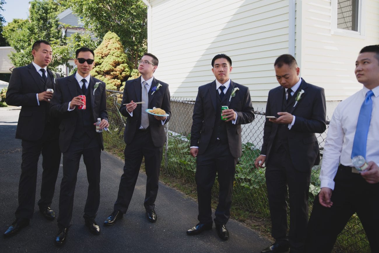 A candid photograph of groomsmen eating and drinking after a vietnamese tea ceremony in Boston