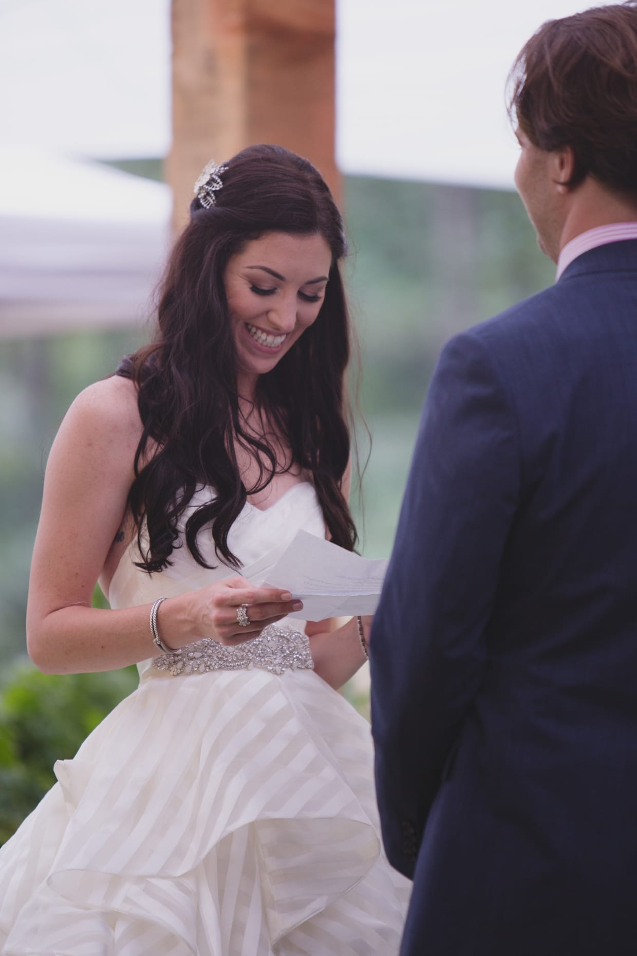 A bride smiles as she reads her wedding vows during a backyard wedding ceremony in Massachusetts