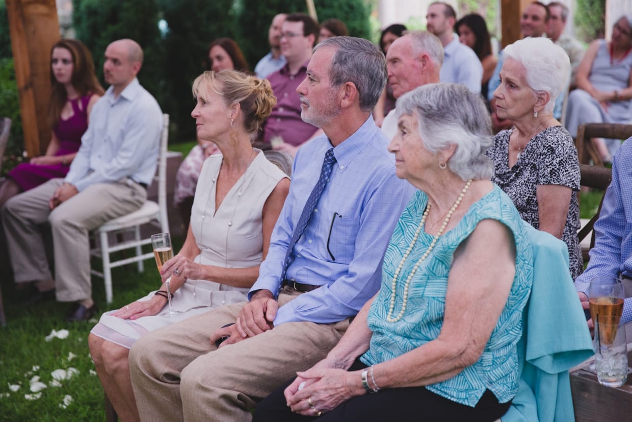 A photograph of the guest watching the bride and groom during their backyard wedding ceremony in Massachusetts