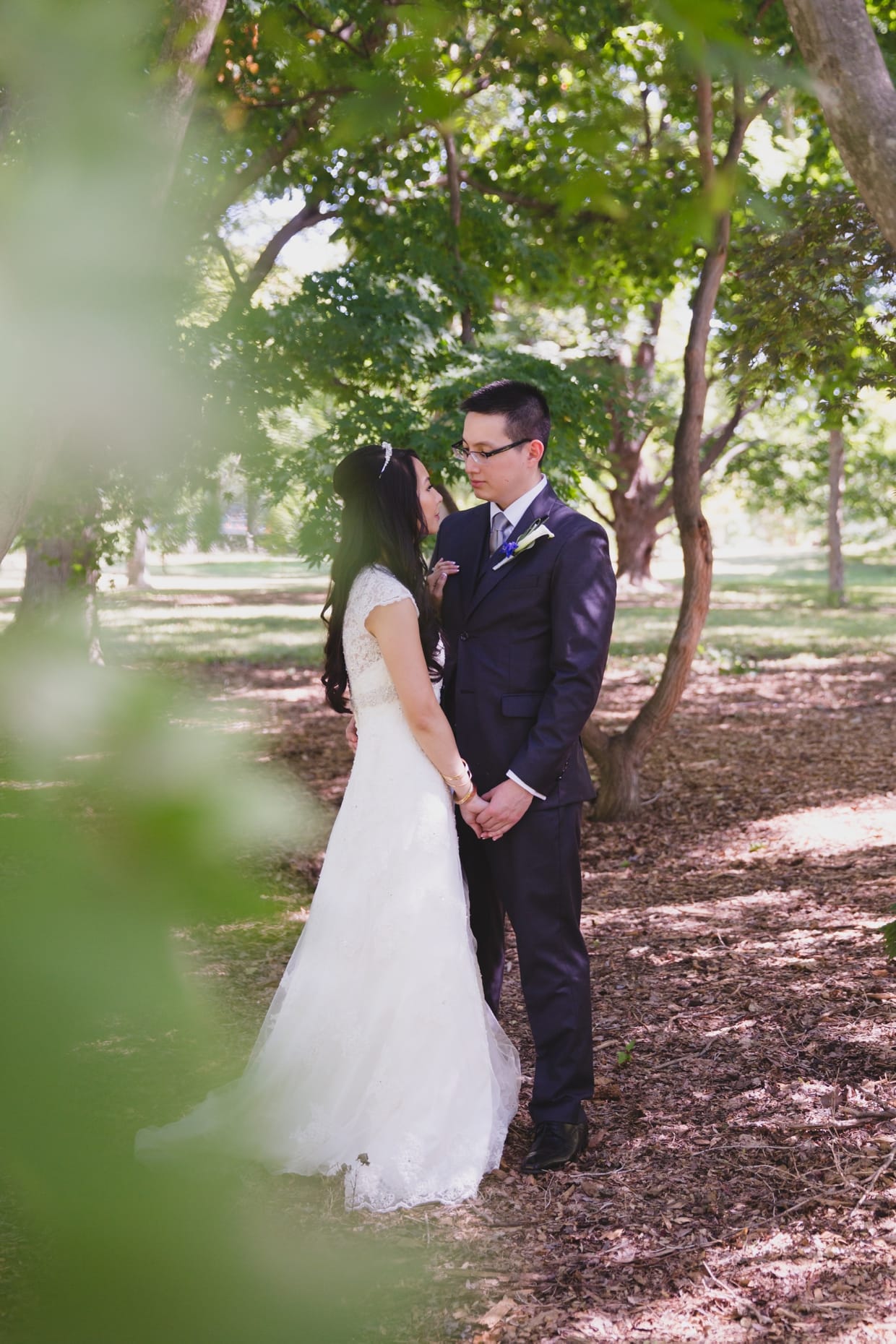 A beautiful portrait of a bride and groom behind a tree in the Arnold Arboretum during their first look